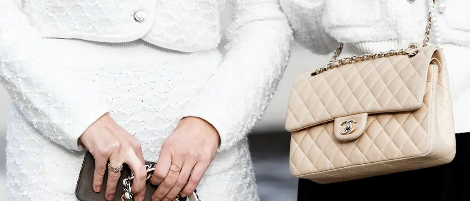 Two women in white tweed carrying beige and white Chanel Classic Flap bags